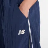 Pantalón deportivo de corte holgado y tiro medio, confeccionado en tejido ripstop de nailon. Presenta un diseño en color azul marino con ribetes laterales en contraste blanco y logo de la marca bordado en la parte superior. Cuenta con cintura elástica y bolsillos laterales.