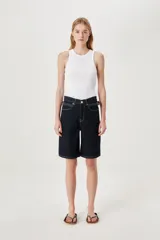 Bermuda de jean de tiro alto y corte ancho, color azul oscuro con costuras en contraste. Presenta detalles de trenzado en la cintura y aberturas laterales.