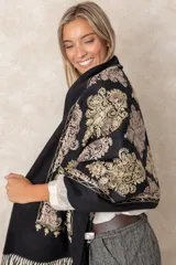 Pashmina de tela densa y suave, con caída pesada y diseño bordado con motivos florales en tonos dorados y beige. Presenta terminaciones con flecos en los extremos.