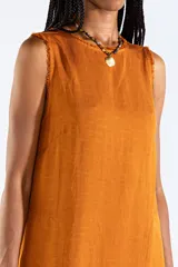 Vestido largo sin mangas de color mostaza, de corte recto y holgado, con escote redondo y bolsillos laterales. Confeccionado en mezcla de lyocell, viscosa y lino.