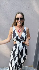 Vestido largo de tela sedosa con estampado de ondas verticales en blanco y negro, escote en V, cut out en la cintura, espalda regulable con lazo y elástico, y tajos laterales.