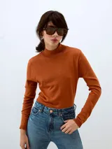 Sweater de punto color ladrillo, con cuello alto y mangas largas.