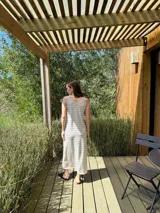 Vestido largo de punto, negro con rayas horizontales blancas, corte recto y sin mangas.