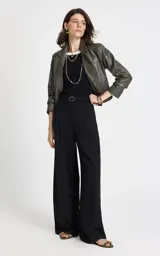 Pantalón sastrero de tiro alto en color negro, con corte ancho y fluido. Presenta pliegues delanteros, cintura estructurada con trabillas y bolsillos laterales. Incluye un cinturón de tela a juego con hebilla metálica ovalada.