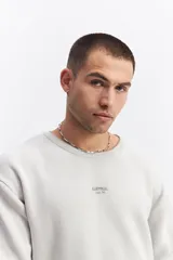 Sweater de algodón de calce relajado, con cuello redondo, mangas largas y puños y ruedo acanalados. Presenta un pequeño logo bordado en el centro del pecho.