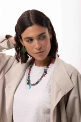 Collar corto de diseño artesanal compuesto por una variedad de cuentas de piedras naturales, cristales checos y acrílicos en tonos multicolor, incluyendo rojo, azul, turquesa y gris. Presenta un dije central en forma de gota color turquesa y cierre con cadena de acero quirúrgico ajustable.