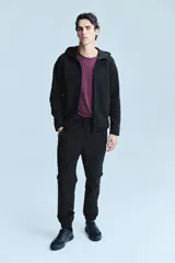 Campera deportiva negra con capucha, cierre frontal y bolsillos laterales con cierre. Confeccionada en tejido funcional efecto neopreno con tecnología DryMove™ para absorber el sudor.