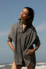 Vestido camisero corto de denim azul, con cuello camisero, cierre frontal con botones y mangas largas con puños abotonados.