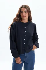 Remera de manga larga color negro, con cuello redondo y cierre frontal de botones. Presenta mangas abullonadas con puños elásticos.