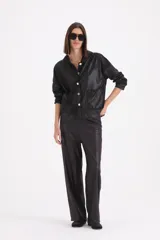 Pantalon de corte recto y holgado, confeccionado en material engomado de acabado satinado en color negro.