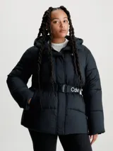 Campera puffer negra de nailon con capucha y cinturón con hebilla. Tiene cierre de cremallera y botón de presión, bolsillos en la cintura y logo monograma de Calvin Klein estampado en el pecho.