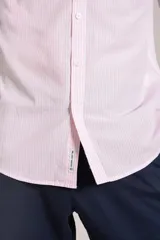 Camisa de manga larga confeccionada en tejido poplin con diseño de rayas verticales finas en color rosado y blanco. Presenta cuello abotonado (button-down), cierre frontal con botones y un bolsillo en el pecho.