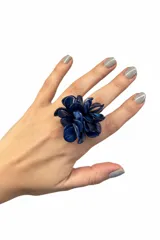 Anillo artesanal con diseño floral compuesto por múltiples pétalos de resina italiana en color azul, montado sobre una base de acero hipoalergénico ajustable.