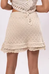 Minifalda color crema de tejido crochet con cintura elástica y volados en el ruedo.