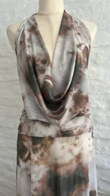 Vestido largo de microtul con estampado abstracto en tonos marrones y blancos, escote halter pronunciado, espalda descubierta y aberturas laterales en la cintura.