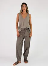 Pantalón beige con diseño a rayas verticales sutiles, corte holgado con puños elásticos en los tobillos y lazo ajustable en la cintura.