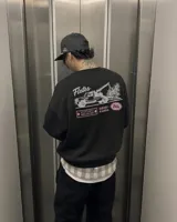 Buzo negro de cuello redondo y manga larga, de corte regular fit. En la espalda presenta un estampado gráfico en color blanco y rosa con la leyenda "Fletes" y el dibujo de una grúa transportando una planta.