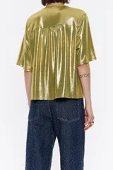 Camiseta verde metalizada de corte recto, con escote pico con pañuelo y lazo a modo de cierre, y manga corta amplia.