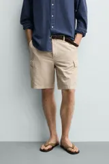 Bermuda cargo regular fit color beige, confeccionada en mezcla de algodón y lino con efecto lavado. Cuenta con bolsillos laterales tipo cargo con solapa en las perneras, bolsillos frontales, cierre frontal con cremallera y botón, y presillas para cinturón.