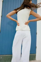 Top tipo chaleco confeccionado en hilatura con viscosa, con diseño de rayas horizontales en blanco y azul marino. Presenta cuello redondo, manga sisa y cierre frontal con botones.