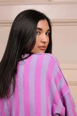 Buzo de manga 3/4 con bolsillo. Estampado a rayas verticales lilas y violetas con terminaciones desflecadas.