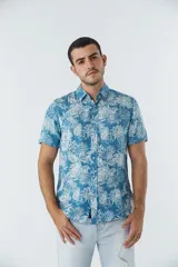 Camisa de manga corta con estampado botánico de hojas en tonos azul y blanco. Presenta cuello clásico, cierre frontal abotonado y corte slim.