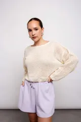 Buzo color crudo de tejido calado con transparencia, de corte holgado y mangas largas.