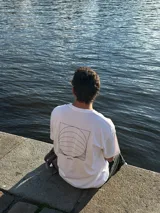 Remera blanca de algodón con corte oversize y estampado en la espalda con diseño geométrico en negro y la palabra 'OSTER' en la parte inferior.