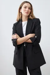 Blazer de corte recto y diseño minimalista, color blanco, con solapas clásicas, bolsillos frontales con solapa y mangas tres cuartos con detalle de botones.