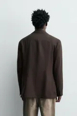 Blazer de corte regular fit confeccionada en tejido de lana italiana. Presenta cuello con solapas de muesca, cierre frontal de un botón, bolsillos de plastrón en el pecho y la cadera, y aberturas en la espalda.