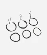 Set de seis pulseras de estilo casual, todas en color negro. Incluye tres pulseras trenzadas ajustables con cordón y tres pulseras con cuentas elásticas (algunas de cuentas lisas y otras de cuentas texturizadas).