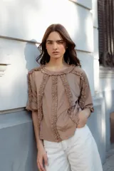 Blusa color beige de manga 3/4 confeccionada en algodón suave, con escote a la base y detalles de volados en 3D que recorren el frente, mangas y escote.