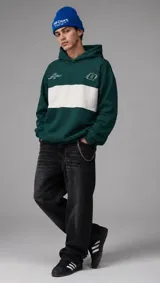 Hoodie verde oscuro con una franja horizontal blanca en el pecho, capucha y bolsillos tipo canguro. Presenta bordados y estampas pequeñas en contraste.