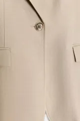 Blazer de corte clásico con cuello solapa y manga larga. Presenta cierre frontal con un botón, bolsillos delanteros con solapa y forro interior a contraste.