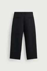 Pantalón relaxed fit marrón oscuro, de corte ancho y recto, con pliegues frontales, bolsillos laterales y cierre con botón y cremallera.