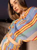 Conjunto de dos piezas compuesto por un top corto de mangas abullonadas con elástico y una falda corta con volados, ambos confeccionados en tela estampada a rayas multicolores.