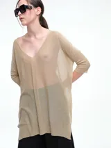 Sweater tipo túnica de tejido liviano con hilo brillante, de corte amplio y holgado. Presenta escote en V, mangas largas y una textura con transparencia sutil.