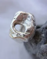 Anillo de plata 925 con diseño irregular y superficie texturizada. Presenta un orificio circular en la parte superior. Talle estándar N 15 (17 a 18 mm de diámetro).