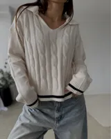 Sweater de punto con diseño de trenzas, cuello en V con solapa tipo polo, manga larga y puños con detalle de franja negra en contraste.