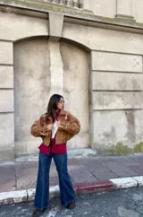 Campera tipo bomber color camel, confeccionada en gamuza, con bordados decorativos en tonos natural y bordó en las mangas y hombros. Presenta cierre frontal y diseño holgado.