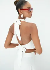 Top blanco de cuello halter con escote drapeado y espalda descubierta, confeccionado en tela de alta calidad con caída fluida.