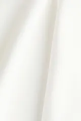 Top en punto roma de color blanco, entallado al cuerpo, con manga japonesa, cuello alto y un delicado peplum con vuelo en la parte inferior.