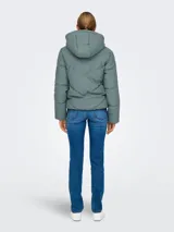 Campera acolchada de corte puffer con capucha, cierre frontal de cremallera y mangas largas con hombros caídos. Presenta un diseño repelente al agua con puños internos elásticos para mayor protección contra el viento.