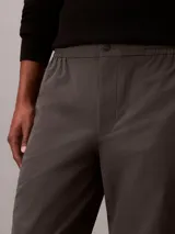 Pantalón tipo jogger de corte regular y estilo formal, confeccionado en tejido elástico de nailon y elastano. Presenta cintura elástica, bolsillos laterales y un diseño de pierna recta con acabado pulido.