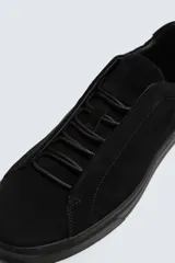 Zapatilla urbana de hombre con parte superior de piel con acabado en serraje color marrón. Presenta un diseño minimalista con cordonera oculta y suela de goma a contraste en color negro.