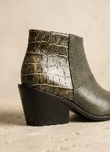 Bota corta de cuero vacuno en color marrón, con diseño de paneles combinados que incluyen textura de reptil en el talón, gamuza en el lateral y cuero liso en la puntera. Presenta un taco cuadrado de 6 cm y suela de caucho antideslizante.