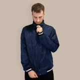 Campera bomber azul de nylon con cuello alto, cierre frontal, puños y cintura acanalados con rayas blancas y grises.