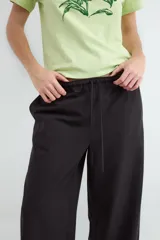 Pantalón negro de corte wide leg, con cintura elástica ajustable mediante cordón y bolsillos frontales.