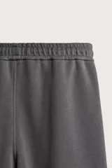 Pantalón jogger de corte relajado confeccionado en tejido de algodón compacto con elasticidad. Presenta cintura elástica ajustable con cordón, bolsillos laterales, bolsillos cargo con solapa en las piernas y detalle de pliegues en las rodillas.