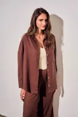 Camisa oversize color marrón, confeccionada en mezcla de viscosa y lino, con cuello clásico, cierre frontal con botones y un bolsillo aplicado en el pecho.